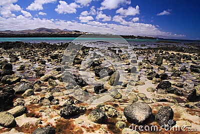 El Cotillo, North Fuerteventura: View over bright scattered stoneson beach in shallow water on turquoise lagoon of beach La Concha Stock Photo