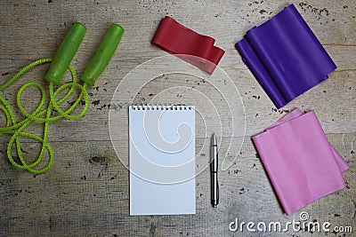 Elastic bands, skipping rope, iron dumbbells and a notebook with a pen. Sports new year. Flat lay Stock Photo