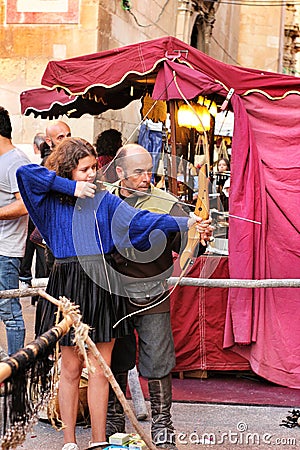 Man teaching a girl archery at a market stall Editorial Stock Photo