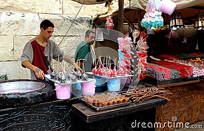 Two handicraftsmen of candies, sugar cotton and caramelized apples at their street stall. Editorial Stock Photo