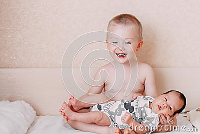 elder little blonde toddler brother boy holding his baby sister Stock Photo