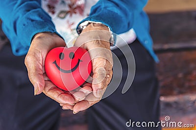 Elder senior women holding read heart with smiling. Close up women hands with red heart, care and healthy concept. Stock Photo