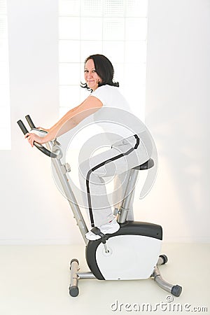 Elder woman on exercise bike Stock Photo