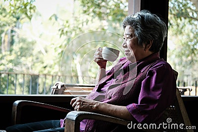 Elder woman holding tea cup on terrace. elderly female relaxing Stock Photo