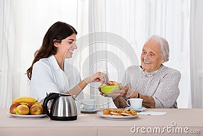 Elder Woman Offering Snack To Nurse Stock Photo