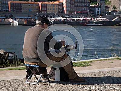 Elderly artist painting by River Douro in Porto, Portugal on a summer day. Editorial Stock Photo