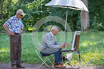 Elderly artist and spectator in the summer park Stock Photo