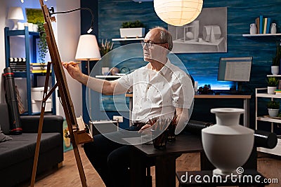 Elderly artist working on vase drawing with pencil on canvas Stock Photo