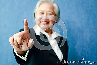 An elderly Asian businesswoman puts her right index finger forward. Stock Photo