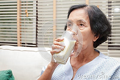 Elderly Asian women drink milk containing calcium to prevent osteoporosis. Stock Photo