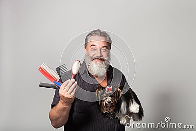 An elderly bearded hairdresser for dogs with a comb and a terrier Stock Photo