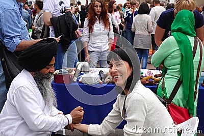 An elderly bearded Indian in a black turban gives a woman an acupressure of the hand Editorial Stock Photo