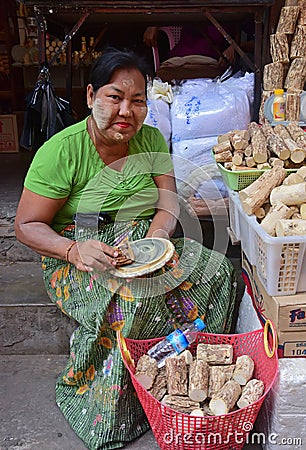 Elderly burmese woman showing how to make fresh Thanaka cosmetic paste Editorial Stock Photo
