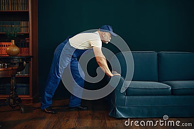 Elderly cargo man in uniform moves sofa Stock Photo