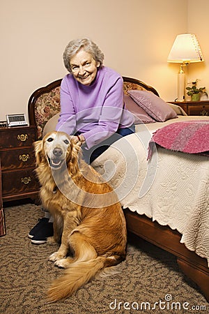 Elderly Caucasian woman in bedroom with dog. Stock Photo