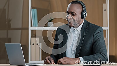 Elderly cheerful businessman African agent broker salesman old 50s man boss in headset has virtual meeting with client Stock Photo