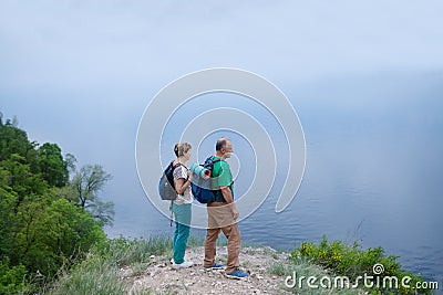 Elderly couple with backpacks travels around mountains. Stock Photo