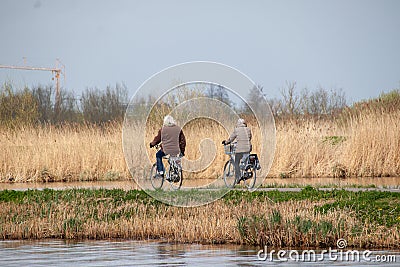 Elderly couple riding bikes at the Dutch Heritage site in Kinderdijk, Netherlands Editorial Stock Photo