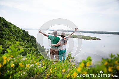 Elderly couple on the top of mountain with hands up. Stock Photo