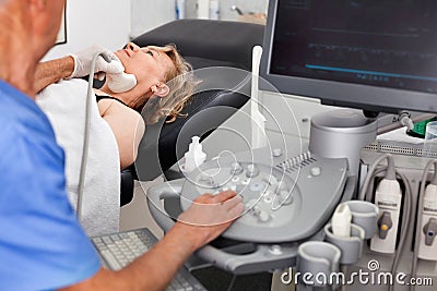 Elderly man sonographer using ultrasonography machine checking female patient in hospital diagnostic room Stock Photo