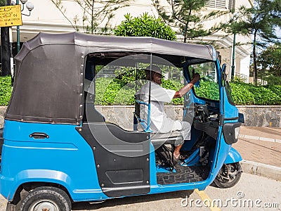 The elderly driver of three-wheeled taxi waiting for passenger during the sunny day. Editorial Stock Photo