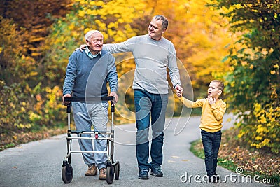 Elderly father, adult son and grandson out for a walk in the park Stock Photo