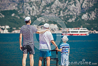 Elderly father adult son and grandson out for a walk at the sea Stock Photo