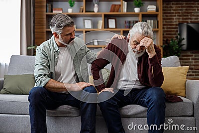 An elderly father complains about life to an adult son, which help him to calm dawn. Two generations family has Stock Photo