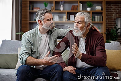 An elderly father complains about life to an adult son, which help him to calm dawn. Two generations family has Stock Photo