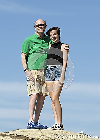 Elderly grandfather and teenage granddaughter standing on a rock Stock Photo