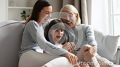 Elderly grandmother her adult daughter and granddaughter having fun online Stock Photo