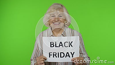 Elderly grandmother holding Black Friday text inscription banner. Senior woman rejoicing discounts Stock Photo