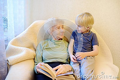 Elderly grandmother and little grandchild reading a book at home. Grandma and grandson Stock Photo