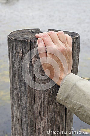 The elderly grandmother rests his right hand on a wooden pillar Stock Photo