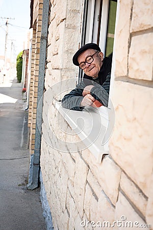 The elderly greets from the window Stock Photo