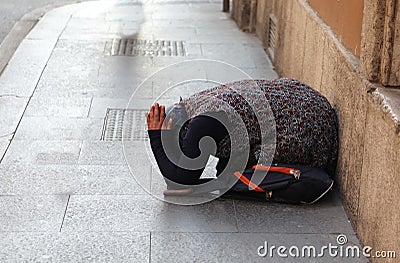 Elderly gypsy woman asking for alms kneeling on the ground with Editorial Stock Photo