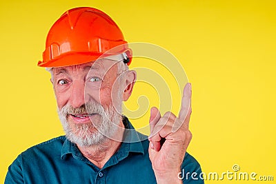 Elderly handsome painting the walls in new a new house with yellow paint,holding roller brush,studio nackground.pointing Stock Photo