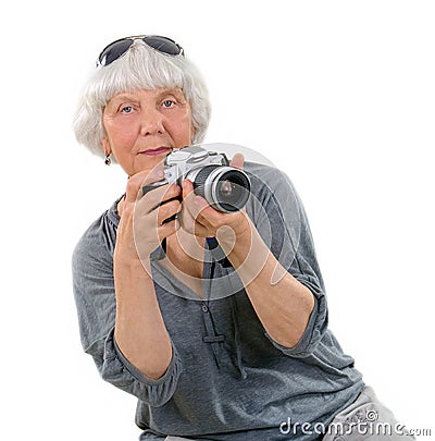 Elderly happy pleasant woman taking pictures with a camera on a white background. Active pension. Leisure and hobbies of people ag Stock Photo