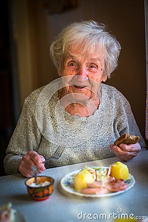 An elderly happy woman eating lunch sitting at the table. Stock Photo