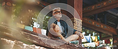 An elderly man with a beard meditates in a Buddhist temple. Peace and tranquility, satisfaction from silence Stock Photo