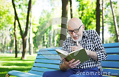 Elderly man in casual reading outdoors Stock Photo