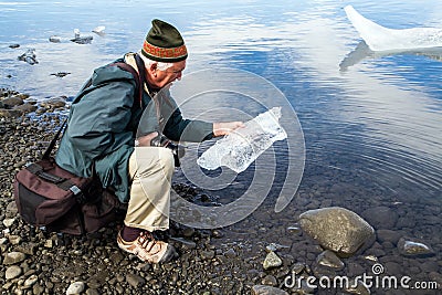 Elderly man examines piece of ice Stock Photo