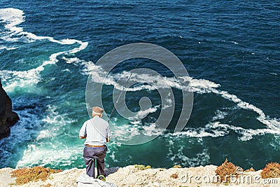 Elderly man fishing with a rod on high cliffs of Sao Vicente Cape, Portugal Editorial Stock Photo