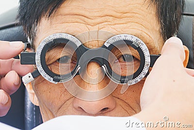 Elderly man having hes eyes examined by an eye doctor on a testing tool in modern clinic, Stock Photo