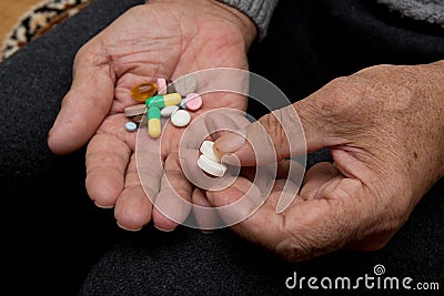 An elderly man holds a lot of colored pills in old hands. Painful old age. Health care of older people. Stock Photo
