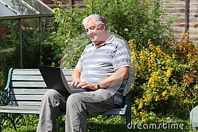 An elderly man with laptop outside. Stock Photo