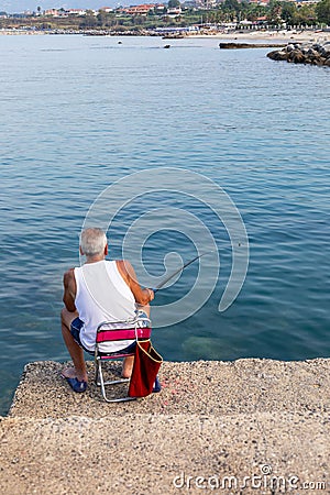 Elderly man is peacefully engaged in a fishing activity on a pier Stock Photo