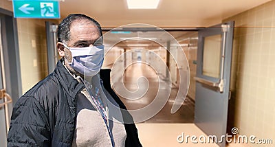 Elderly man in protective medical mask isolated against empty hospital corridor. Coronavirus elderly advice. Safety old men. Stock Photo