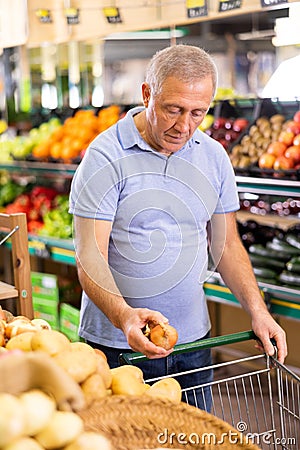 Elderly man purchaser buying onions in grocery store Stock Photo
