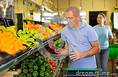 Elderly man purchaser buying pepper in grocery store Stock Photo